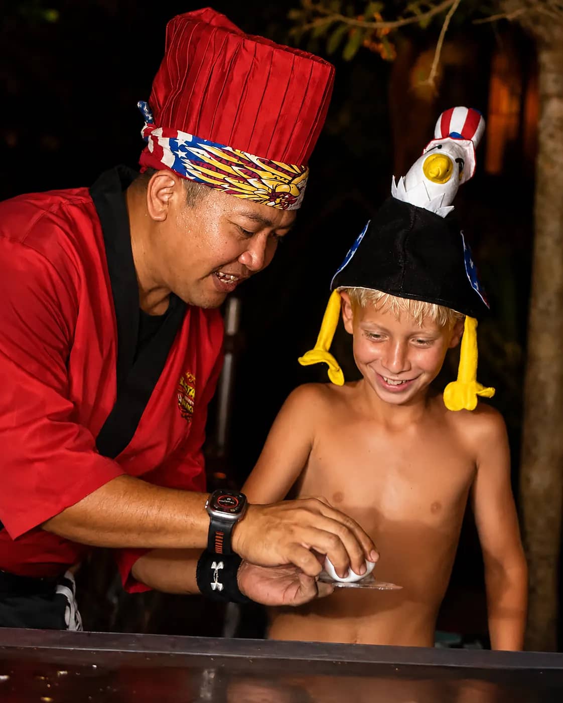 Chef and a young guest during a hibachi egg trick at a private party