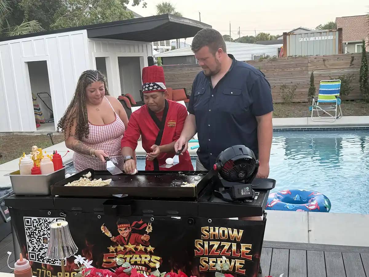 Chef cooking with guests at a backyard hibachi station
